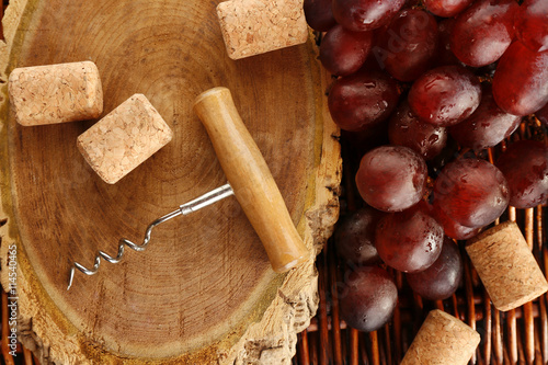 Wine corks and tailspin with bunch of grapes on wooden background photo