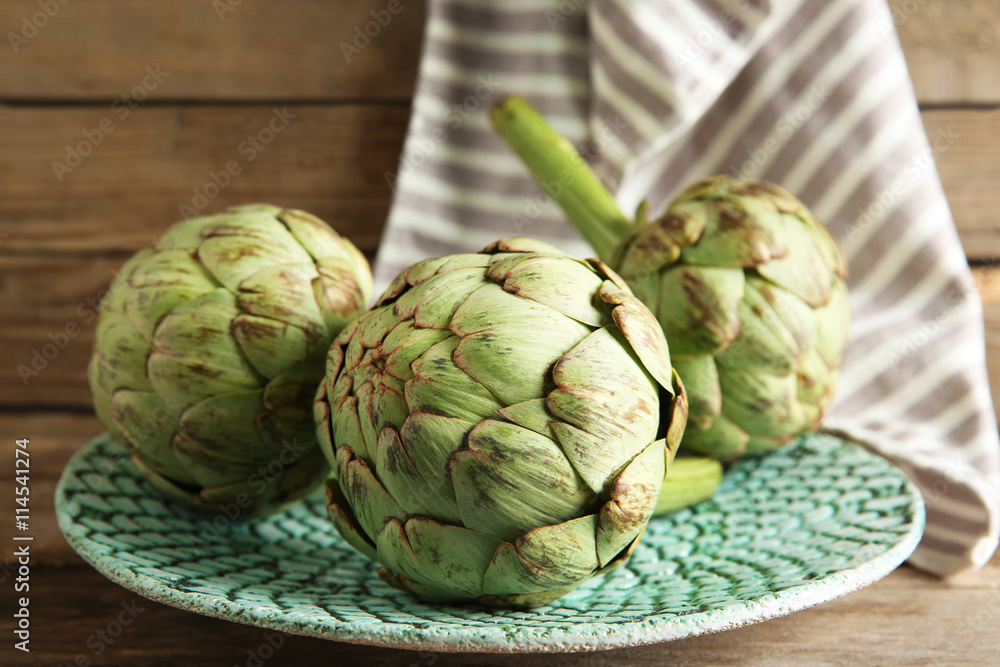 Fototapeta premium Artichoke on plate on wooden background