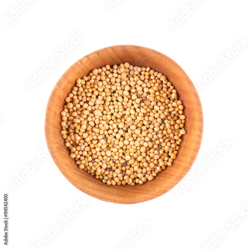 Mustard seeds in small wooden bowl isolated on white