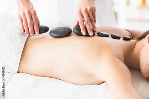 Masseur giving hot stone massage to woman