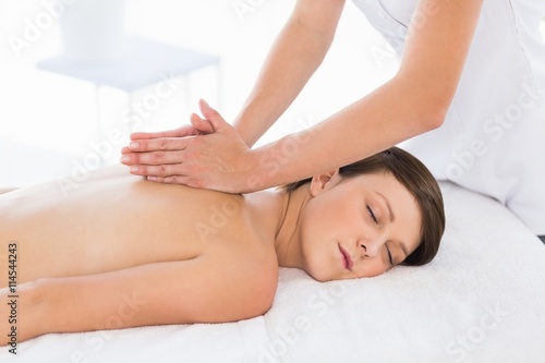 Masseuse giving back massage to naked woman