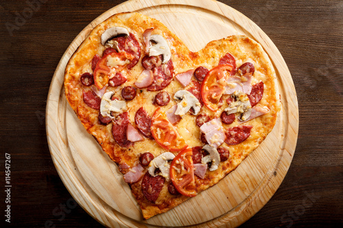Pizza heart shape on dark wooden background top view