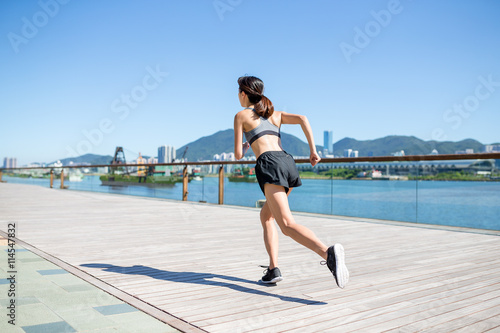 Back view of woman running in seaside boardwalk © leungchopan