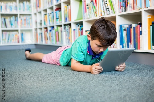 Boy using digital tablet in school library