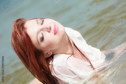 Sensual girl wet cloth in water on the coast.