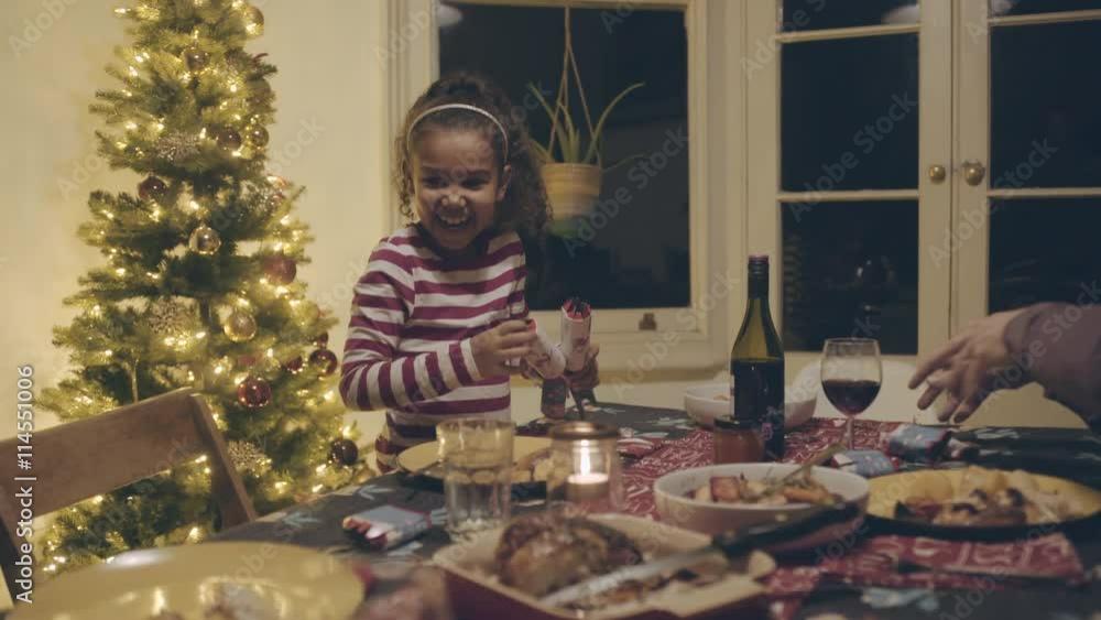 Mixed race family opening Christmas crackers Mixed race family opening Christmas crackers
