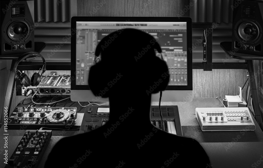 Naklejka premium Człowiek produkuje muzykę elektroniczną w domowym studio projektu. Sylwetka. Czarno-białe zdjęcie.