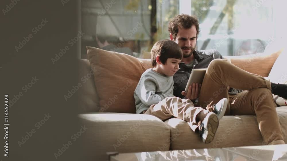 Father and son on the couch using digital tablet Father and son on the couch using digital tablet