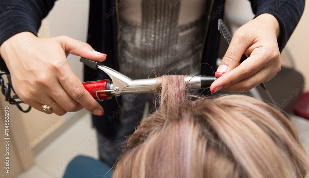 Naklejka premium wrap hair curling in a beauty salon