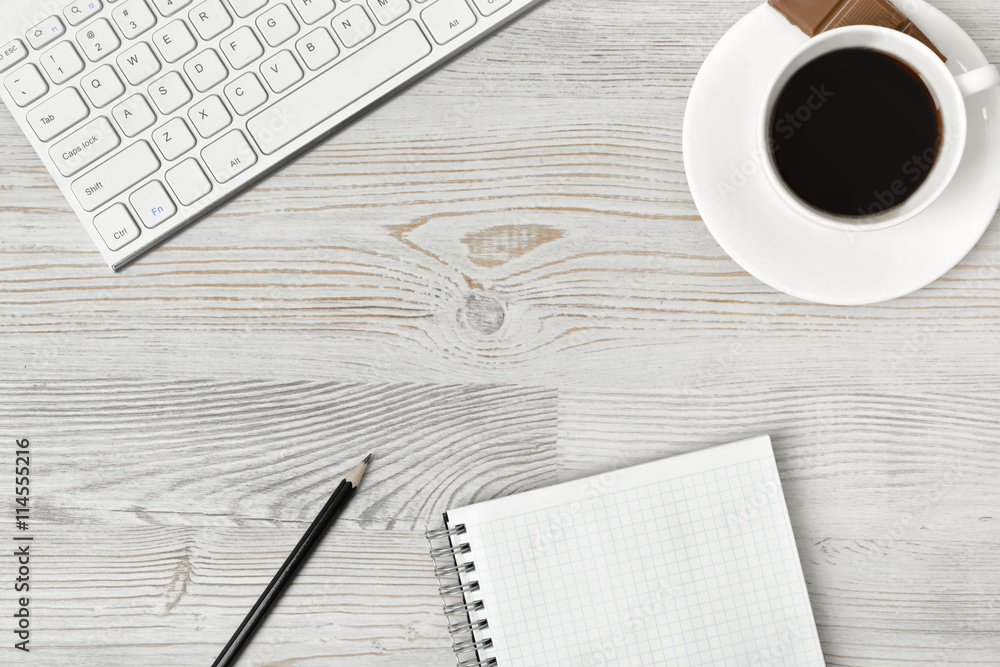 Workplace with cup of coffee, keyboard, smarthphone, white sheets and pen on wooden surface in top view. Workplace with cup of coffee, keyboard, smarthphone, white sheets and pen on wooden surface in top view.