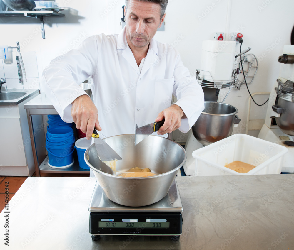 male cook weighting honey with a spatula in commercial laboratory male cook weighting honey with a spatula in commercial laboratory