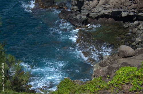 Tropical ocean waves splashing against lava rock shoreline in Maui, Hawaii
