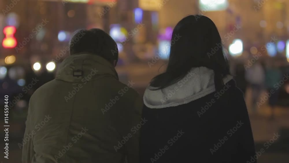 Couple of teenagers hanging out in crowded night city street, friends talking Couple of teenagers hanging out in crowded night city street, friends talking