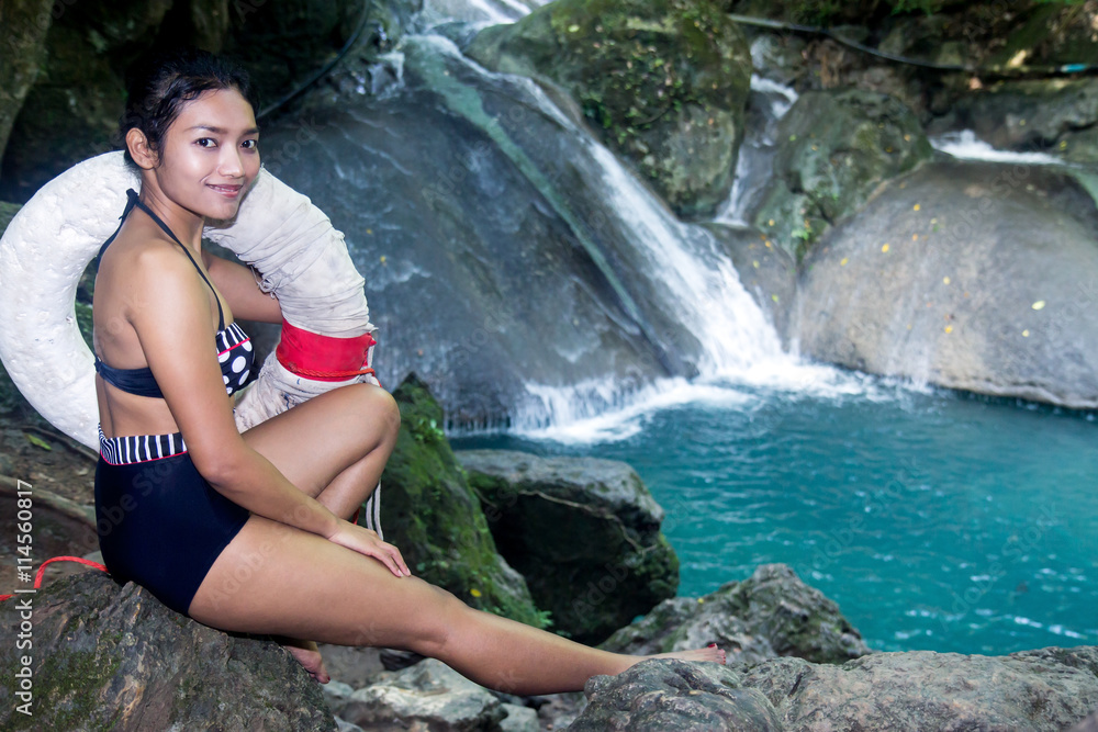 woman with lifebuoy sitting on the shore of the waterfall