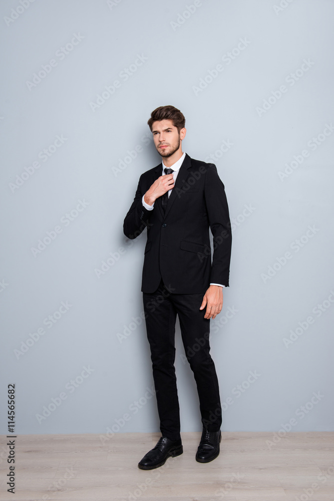 Full length portrait of young businessman in black suit correcti Full length portrait of young businessman in black suit correcti