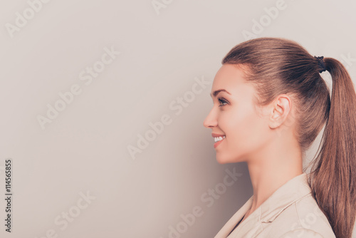 Side view of young smiling businesswoman isolated on gray backgr