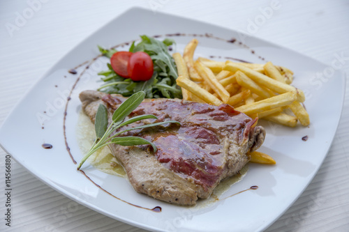 Pork steak in white plate and french fries .
