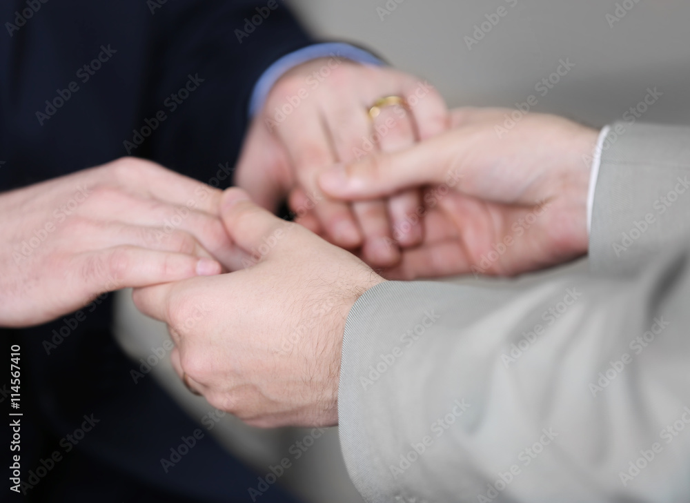 Two homosexuals holding each other hands on blurred background