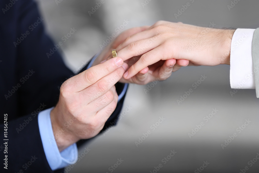 Fototapeta premium One groom placing the ring on another man's finger