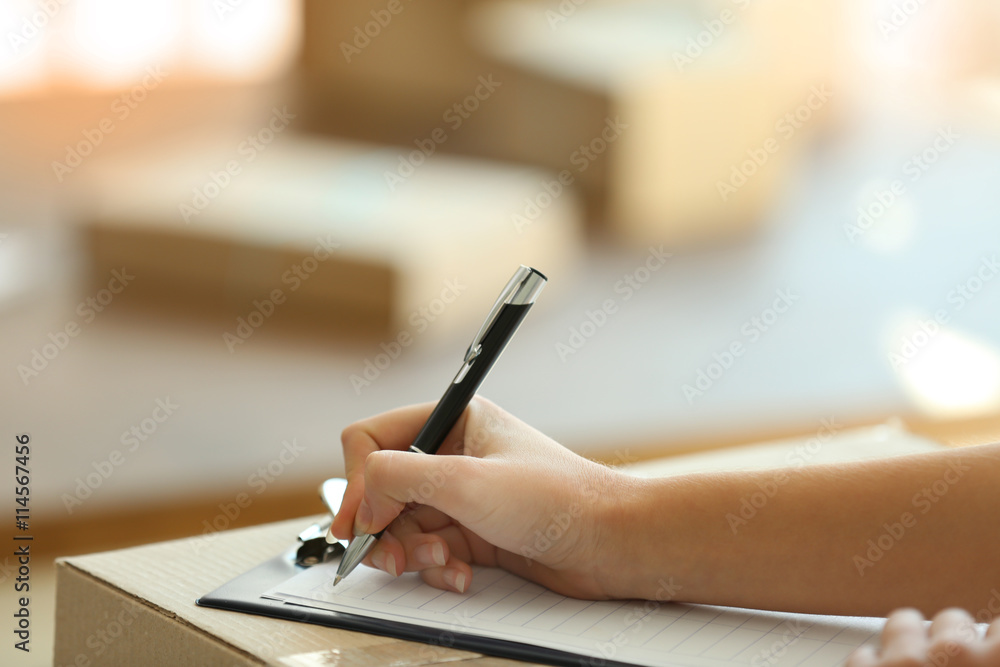 Fototapeta premium Delivery concept. Woman signs papers among parcels, close up