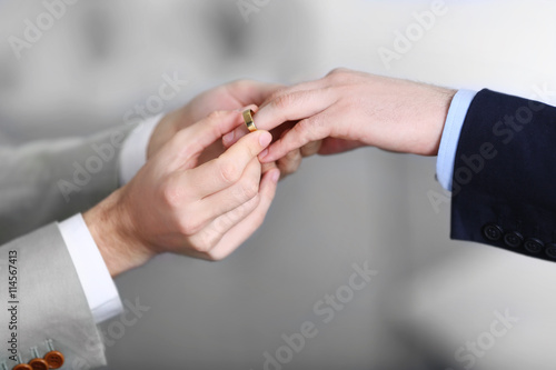 One groom placing the ring on another man's finger