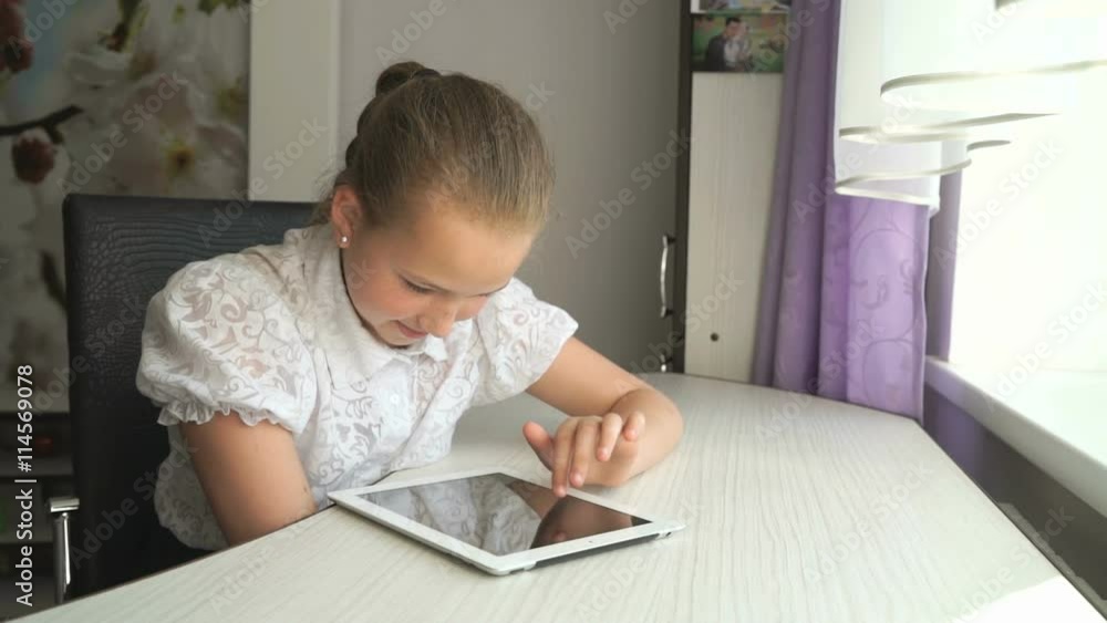 Cute little girl uses a digital tablet computer Cute little girl uses a digital tablet computer
