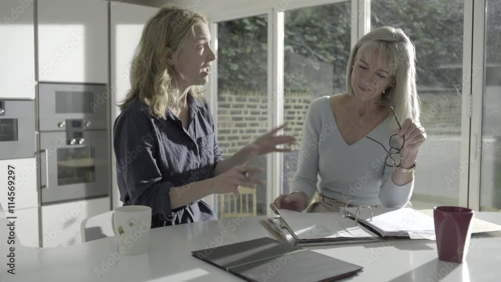 Adult woman with senior mother looking at personal finance in kitchen Adult woman with senior mother looking at personal finance in kitchen