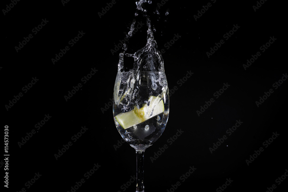 Toss fruit into a glass of splash water and black background Toss fruit into a glass of splash water and black background