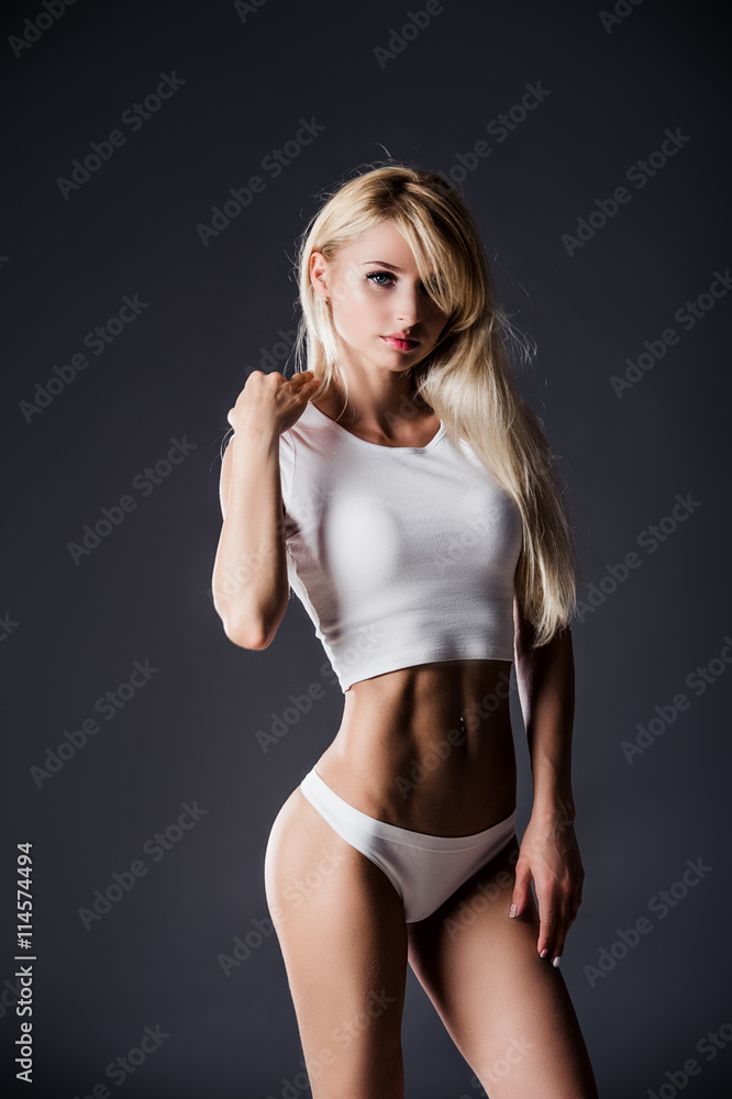 Naklejka premium beautiful female sporty young woman in white lingerie with excellent fit shape over grey studio background