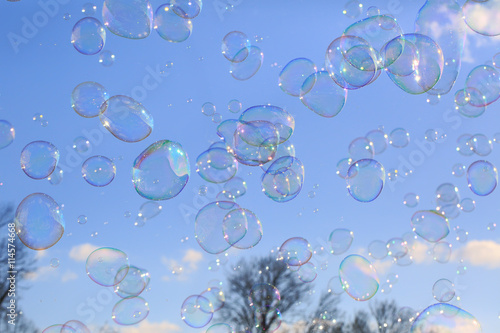 Delicate soap bubbles floating in a blue sky