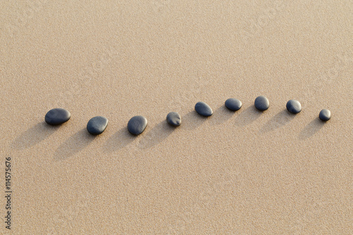set of hot stone on white sand calm beach in backbone shape. sel