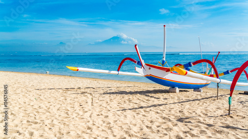Traditional Indonesia fishing outrigger canoe on a beautiful tropical sandy beach in Bali.