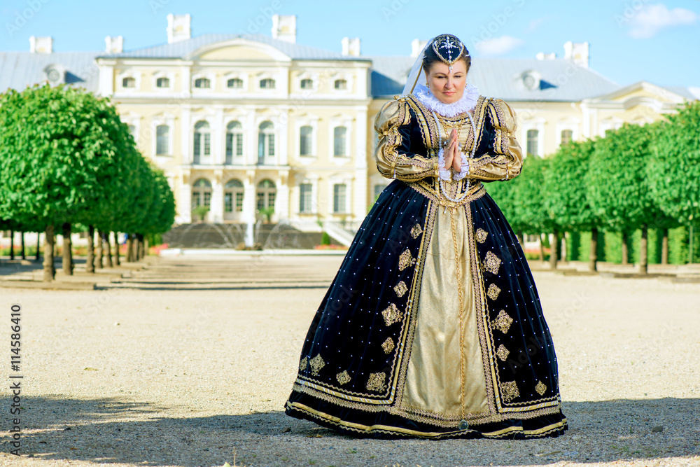 Historical cosplay. Beautiful woman in the similitude of Marguerite of Navarre, queen of France ancient dress in the garden near palace
