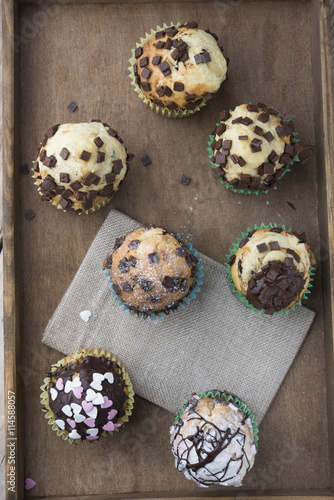 Photo of tasty cupcakes with chocolate over wooden table