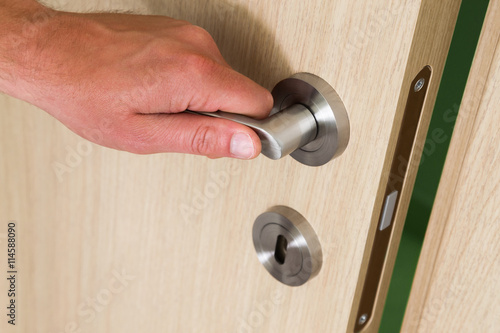 Male hand opening a wooden door