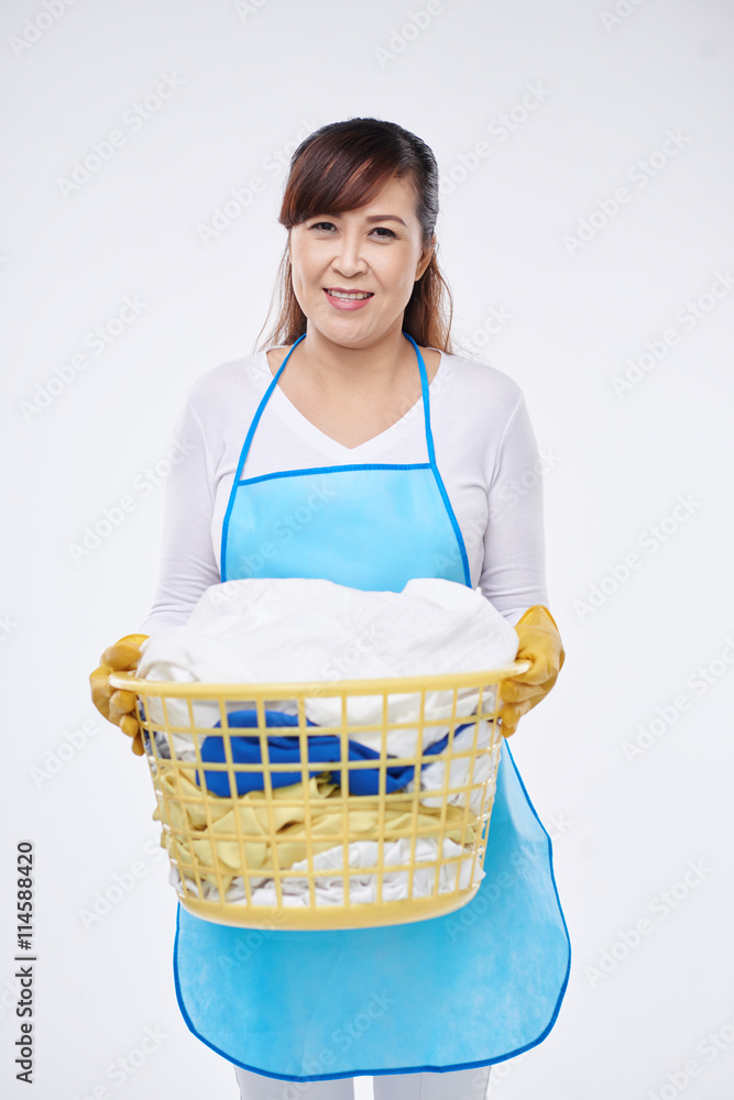 Smiling housewife holding basket with dirty clothes Smiling housewife holding basket with dirty clothes