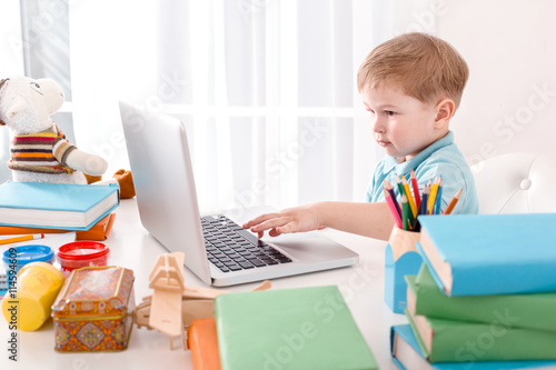 Cute boy absorbedly using laptop