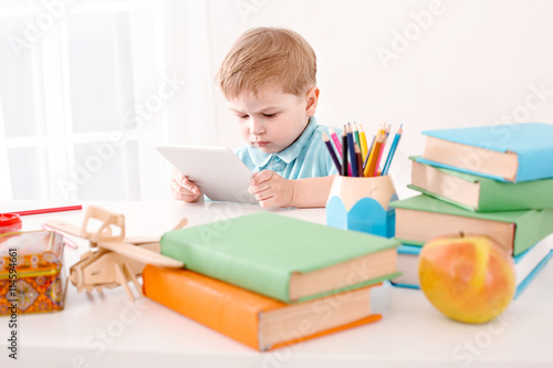 Cute boy absorbedly using tablet computer photo