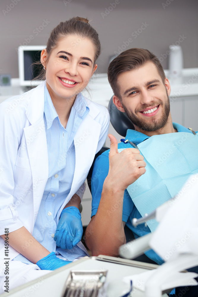 Happy young man in a dentist's chair giving a thumbs up. - obrazy, fototapety, plakaty 