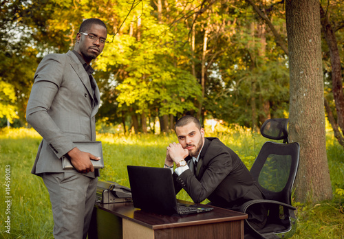 Two young businessman at work in the park.