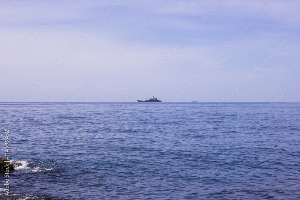 Blue sea surface with waves, sky and a ship on the horizon. Summer seascape