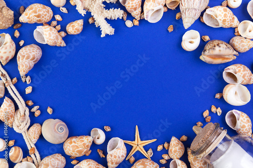 Colorful marine items - seashells, starfish, coral, bottle with note and rope arranged as frame. Top view with copyspace