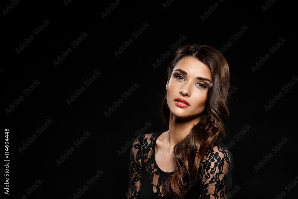 Portrait of beautiful girl in black dress over dark background