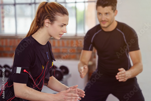 Fotografie trainer betreut eine kundin beim ems-training im studio
