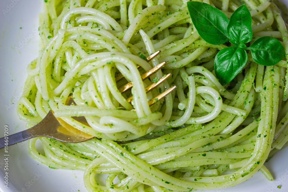 pasta with pesto sauce and basil leafs on white plate, wood background, top view pasta with pesto sauce and basil leafs on white plate, wood background, top view