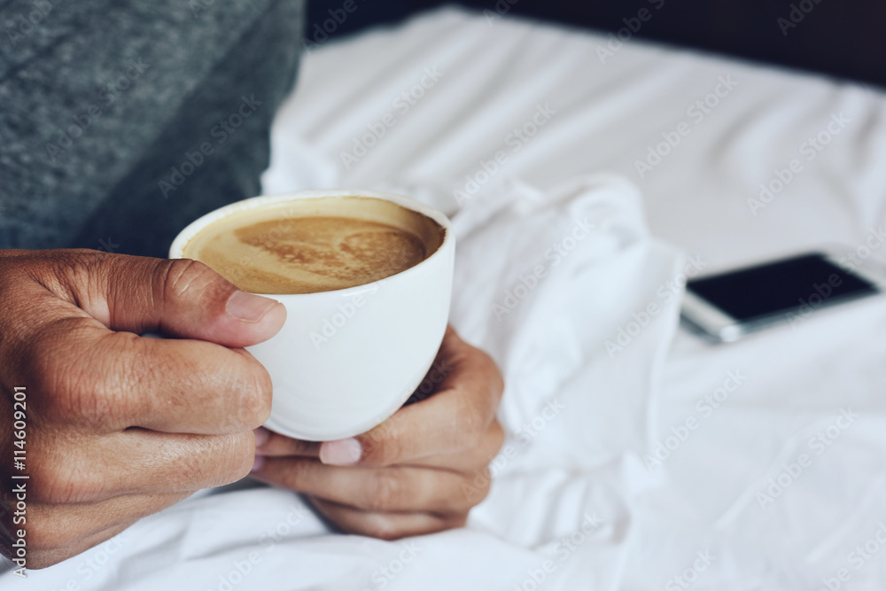 young man having a coffee in bed