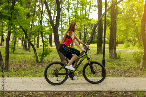 Happy girl cyclist riding on a mountain bike outside © Artem