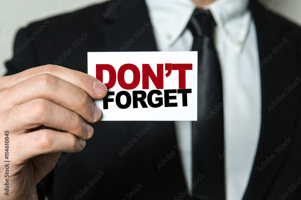 Business man holding a card with the text: Don't Forget Business man holding a card with the text: Don't Forget