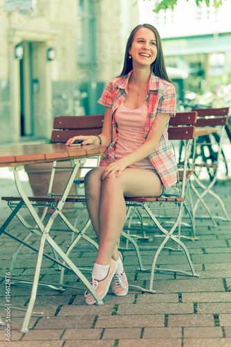 Young woman wearing shorts seat at table in street cafe and smiling © luchschenF