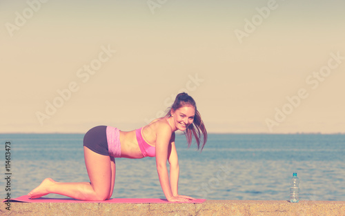 Woman doing sports exercises outdoors by seaside © Voyagerix